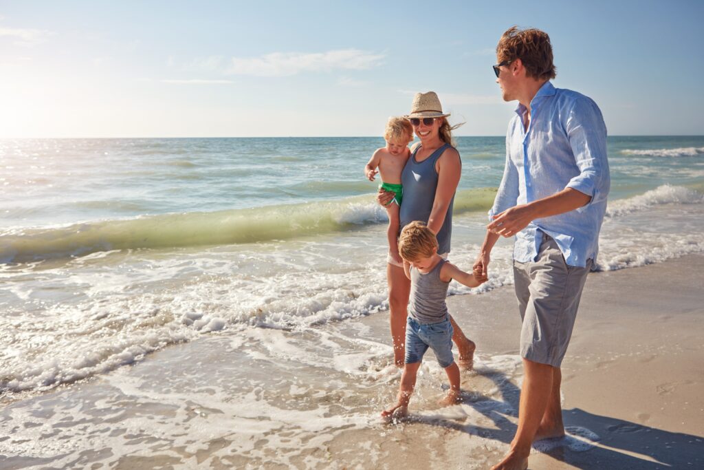 Holding hands, smile and sea with family at beach for trust, connection and summer vacation. Bonding, support and travel with parents and children outdoor for love, commitment and holiday space